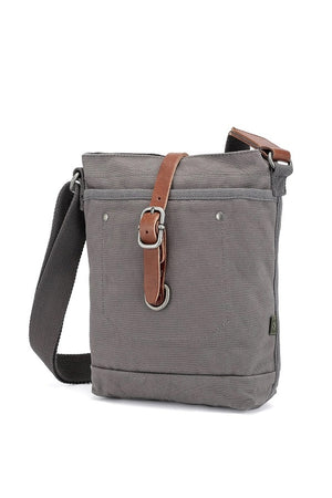 The TSD BRAND Forest Zip Crossbody Bag in Grey features a wide black strap, brown leather buckle accent, metal rivets, and a subtle side logo tag for a military-inspired look.
