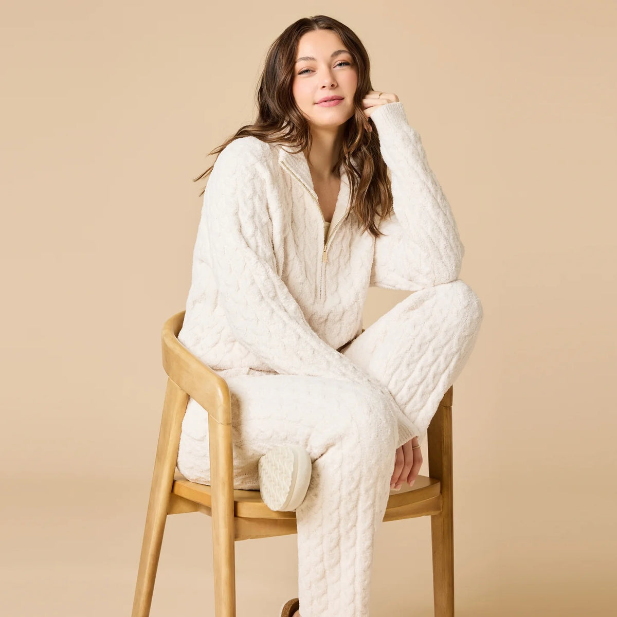 A woman wearing a marshmallow-soft, cream-colored SOFTIES - CABLE KNIT MARSHMALLOW ½ ZIP WITH TAPERED PANT SET, featuring a half-zip pullover and matching pants with a drawstring waist.