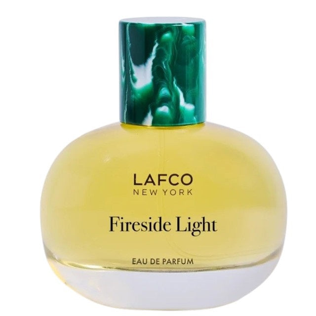 A round glass bottle of LAFCO Fine Fragrance, Fireside Light 50ml, a vegan perfume with a long-lasting scent, contains yellow liquid and is topped with a marbled green cap, displayed against a plain white background.