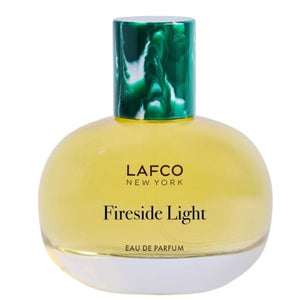 A round glass bottle of LAFCO Fine Fragrance, Fireside Light 50ml, a vegan perfume with a long-lasting scent, contains yellow liquid and is topped with a marbled green cap, displayed against a plain white background.