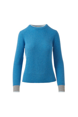 A woman with long brown hair models the KINROSS Tipped Thermal Cashmere Crewneck Sweater in burnt orange with dark gray cuffs, paired with blue jeans, standing against a plain white background.