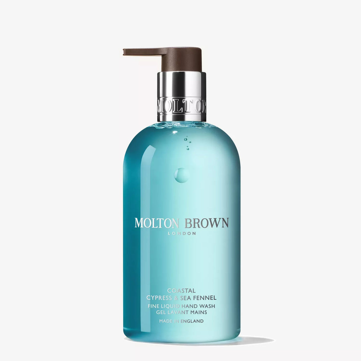 A clear blue bottle of MOLTON BROWN - COASTAL CYPRESS HAND WASH with a dark pump dispenser stands against a white background, highlighting its fresh marine notes and seashore-inspired scent.
