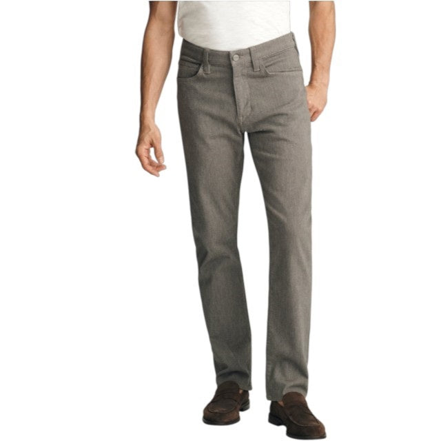 A man stands against a plain background wearing a dark brown sweater layered over a light collared shirt, paired with 34 HERITAGE - COURAGE STRAIGHT LEG PANTS IN STONE DIAGONAL by 34 HERITAGE, and brown shoes. One hand rests in his pocket and he maintains a neutral expression.