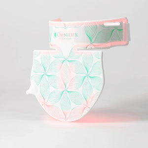 Box contents labeled: OMNILUX - CONTOUR NECK & DECOLLETE KIT by OMNILUX, featuring a flexible silicone LED device for red light therapy, rechargeable battery controller, two straps, power supply with plug adaptors, and a carry bag. The packaging is open with all items neatly arranged for your anti-aging skincare routine.