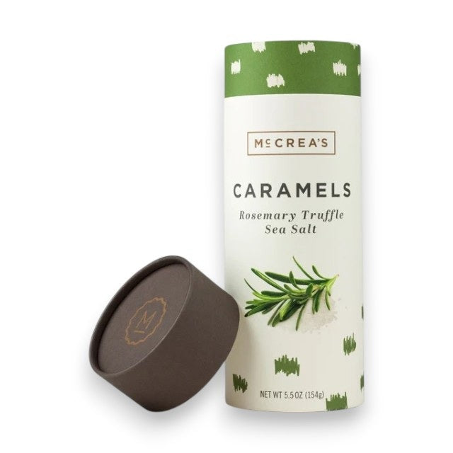 A cylindrical container of McCREA'S CANDIES ROSEMARY TRUFFLE SEA SALT CARAMELS features a green and white design with rosemary and sea salt illustrations. The brown lid is shown next to the container.