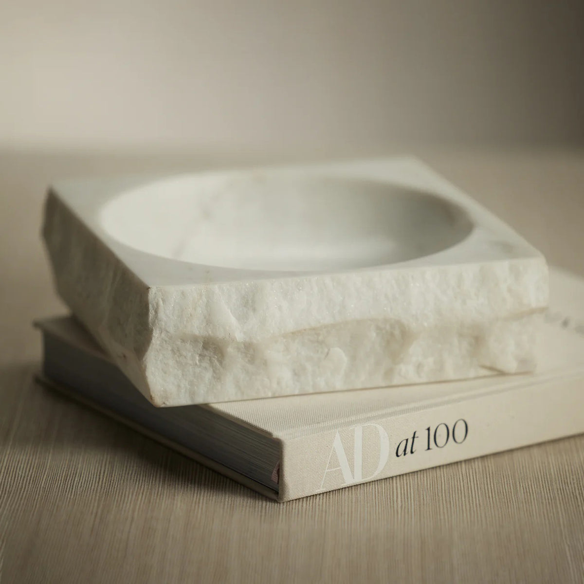 The ZODAX ROCK FINISH MARBLE SQUARE BOWL is crafted from premium white marble, featuring rough, unfinished edges and a smooth, shallow center.
