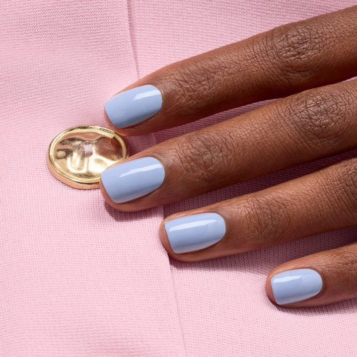 A white nail polish brush spreads MANUCURIST - GREEN™ NAIL POLISH IN LILAS by MANUCURIST INC, a pale lavender vegan formula, smoothly across the surface to create a glossy, even layer.