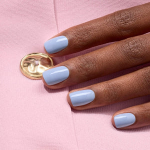 A white nail polish brush spreads MANUCURIST - GREEN™ NAIL POLISH IN LILAS by MANUCURIST INC, a pale lavender vegan formula, smoothly across the surface to create a glossy, even layer.