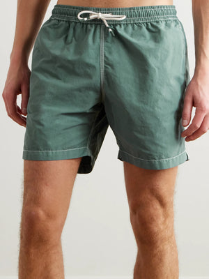 A pair of HARTFORD nylon swim trunks in Faded Kelly with white stitching and side pockets, shown flat on a light background. Includes travel pouch.