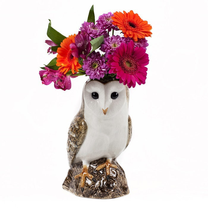 The QUAIL CERAMICS - BARN OWL VASE by QUAIL DESIGNS features colorful flowers like orange and pink gerbera daisies and purple blooms, arranged to mimic owl feathers. Handpainted stoneware, dishwasher safe, shown on a plain white background.