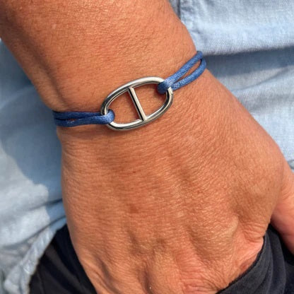 The STOLEN RICHES Viseu String Bracelet features a light blue cord, an adjustable knot design, and a silver anchor chain fixture centerpiece.