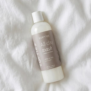 A bottle of SOFTIES - ALL DAY WASH™ LAUNDRY DETERGENT on a white textured surface.