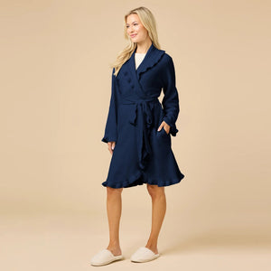 A woman wearing a SOFTIES - RUFFLE CHENILLE ROBE 36″ IN MIDNIGHT, a knee-length navy blue chenille robe with cascading ruffle trim.