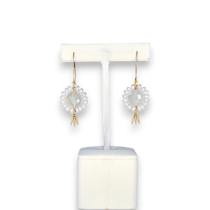 The GOLDISH - Floral Gemstone Earrings in Moonstone and White Pearl feature a circular, faceted moonstone center surrounded by white pearls, with three gold danglers, all set in 14K gold fill. Displayed on a white stand against a dark background.