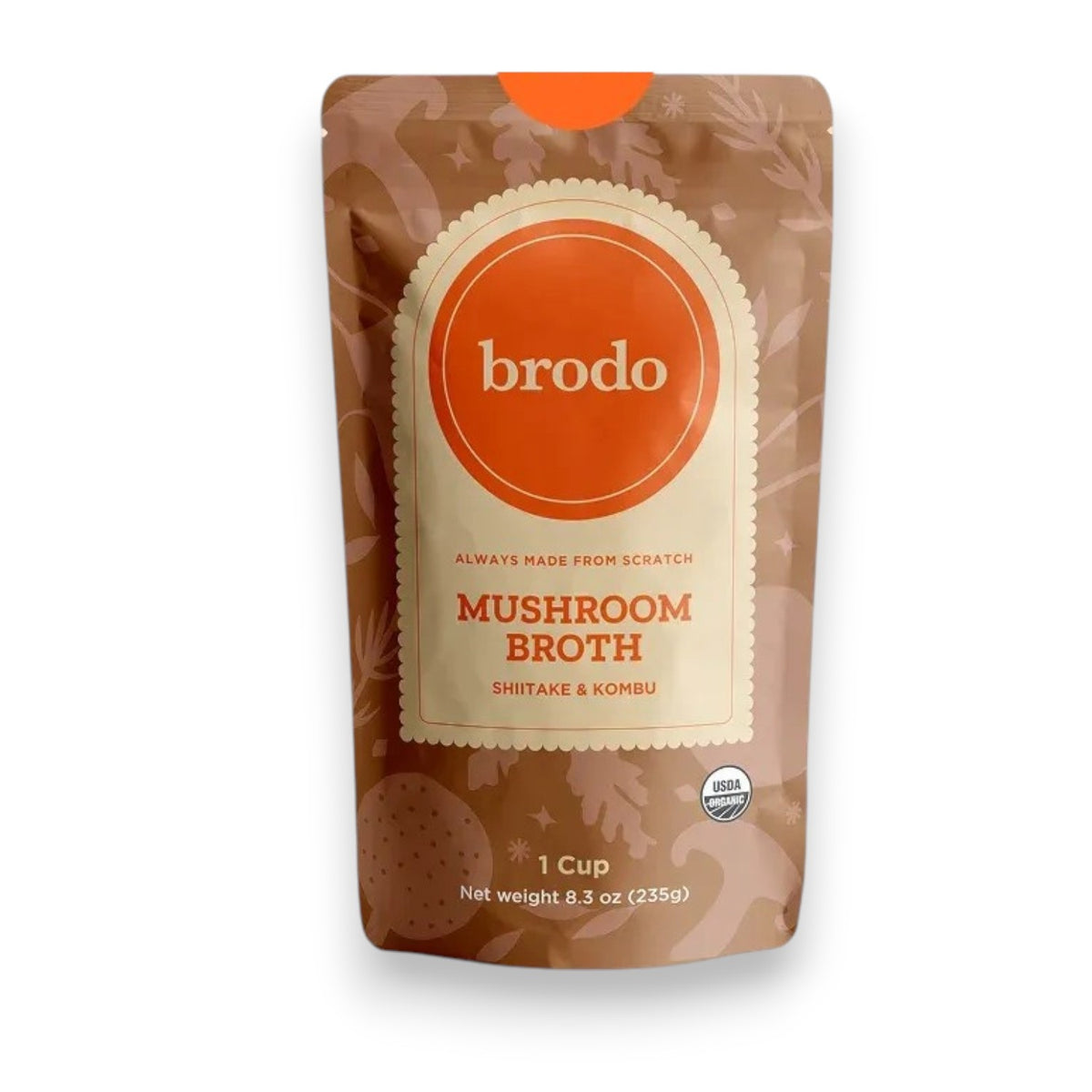BRODO BROTH COMPANY’s BRODO BROTH- MUSHROOM ORGANIC pouch sits on a table amidst dried seaweed, whole mushrooms, and a bowl of broth, creating an earthy, natural scene that emphasizes this keto-friendly and dairy-free option.