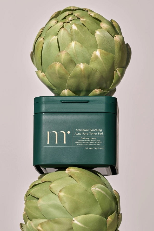 A dark green square container with a lid, labeled &quot;MOLVANY - Artichoke Soothing Affect Pore Toner Pads&quot; by HONG CHEON USA, INC. Tailored for acne-prone skin, this &quot;ordinary luxury&quot; item provides comfortable and luxurious care for sensitive skin.