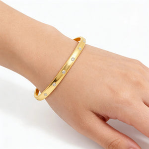 The ELLA STEIN Lucky 7 Cuff Bracelet by ELLA STEIN is a delicate, open gold-plated bracelet featuring evenly spaced small round diamonds, shown against a plain white background.
