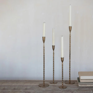 A close-up of the CREATIVE COOP CAST IRON TAPER HOLDER IN BRASS FINISH, EXTRA LARGE, featuring a textured vertical ribbed pattern and a rounded tapered cup at the top, set against a plain white background.