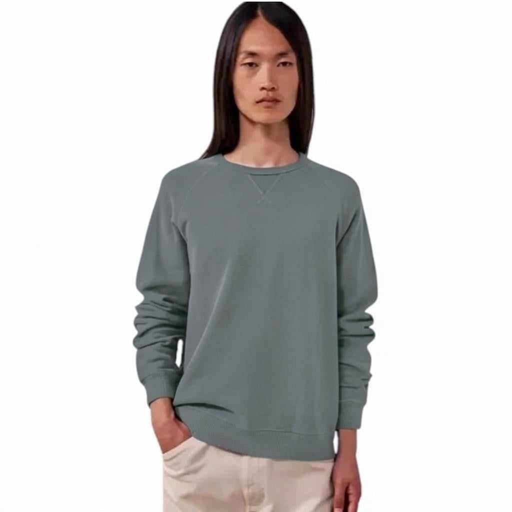 A close-up view of a person wearing the HARTFORD light fleece sweatshirt in charcoal, made in Portugal, featuring a distinctive X-shaped decorative stitch detail at the base of the collar.