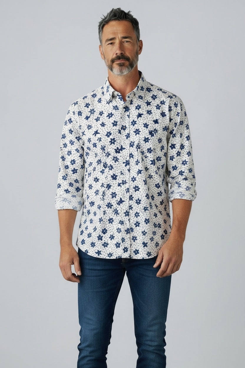A man with short gray hair and a beard wears the FRANK & EILEEN Finbar Men's Button Up Shirt in Blue and White Small Flowers Big Flowers. He pairs it with dark jeans, standing against a plain white background for an everyday look.