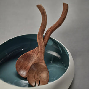 The ZODAX MANGO WOOD CURVY SALAD SERVER SET features two handcrafted servers—a spoon and fork—with a wavy design, crafted from mango wood for elegant dining. Set is displayed on a white background.