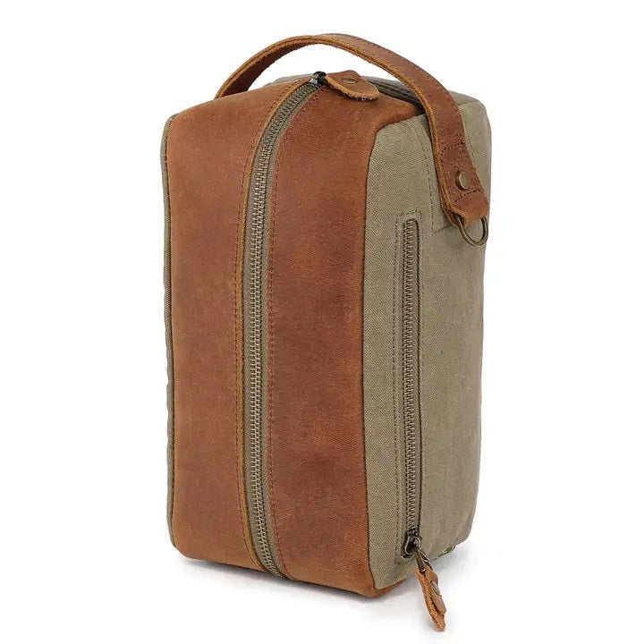 The TSD BRAND Valley Oak Toiletry Bag in olive is a rectangular, handcrafted travel essential made from durable canvas, featuring a tan leather strap and a small leather patch for added style.