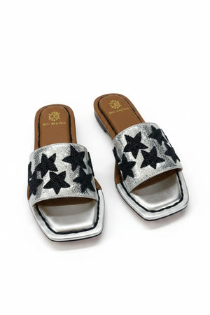 The DE SIENA DA SIENA - BEADED STARS SLIDES are brown and gold metallic open-toe leather slides with a wide strap featuring black beaded star designs and a gold insole outlined in brown with "DE SIENA" branding near the heel.