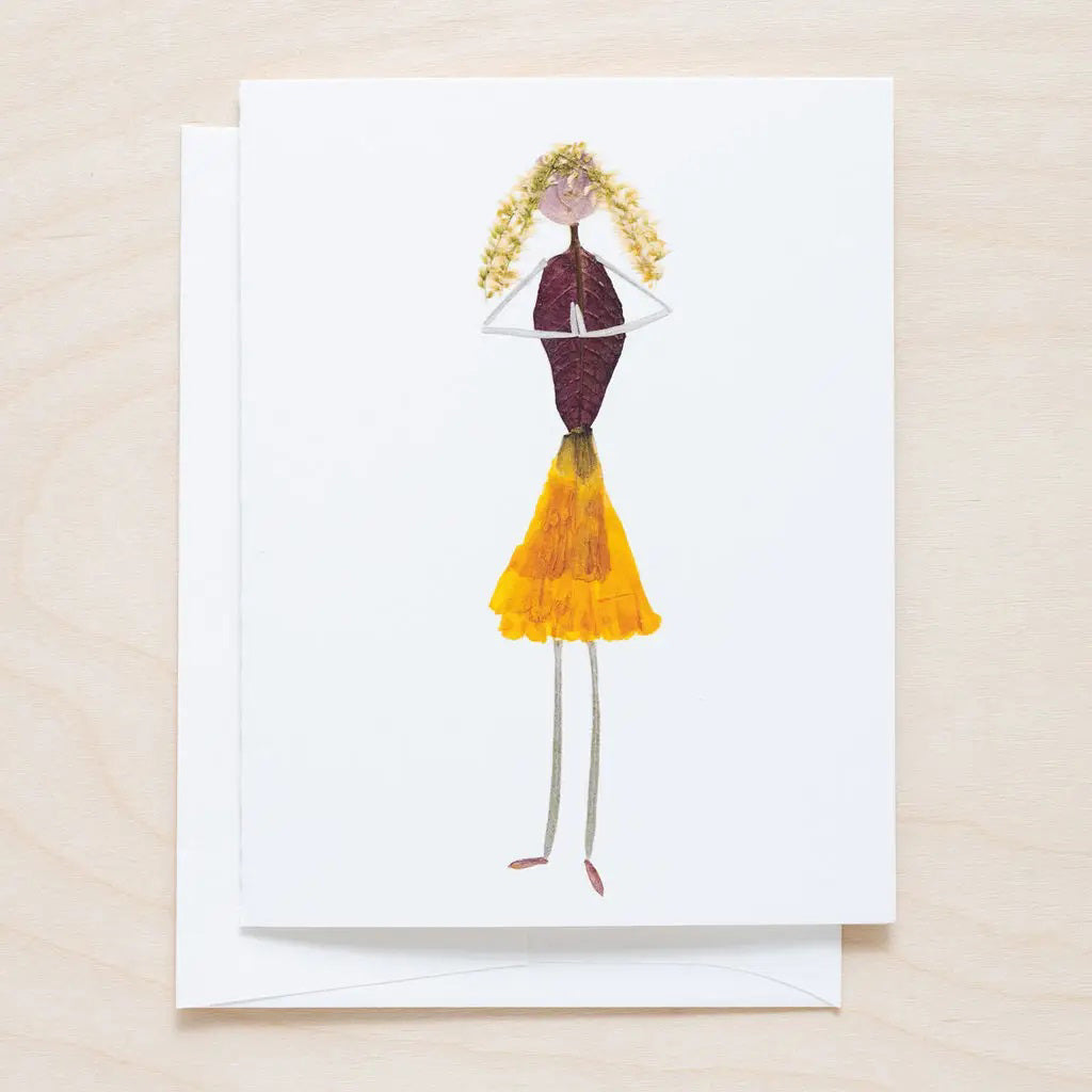 The PETAL PEOPLE PRESS - GRATITUDE CARD features a creative drawing of a girl made from dried leaves and petals on white paper, styled as botanical art, and shown on a white table with paper clips, a black tool, and green leaves.
