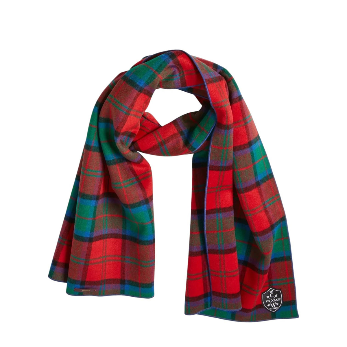 The CLIFTON WILSON - RED MULTI PLAID WOOL SCARF features 100% Italian wool in a striking red, blue, and green tartan plaid pattern. Neatly draped with a knot, this classic scarf is finished with a small black and white embroidered patch in one corner—a subtle touch that reflects the refined quality of CLIFTON WILSON craftsmanship.