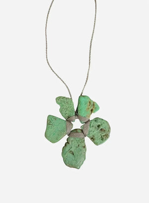 The ANN LIGHTFOOT - ROUGH CUT CHRYSOPRASE FLOWER NECKLACE by ANN LIGHTFOOT features four irregular green chrysoprase stones arranged in a flower-like shape, secured with wrapped cord and suspended from a delicate silver chain, shown against a white background.