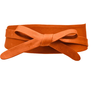 The ADA WRAP BELT IN PAPAYA, an orange leather belt with a twisted design, is handmade by artisans using genuine Argentinian vegetable-tanned leather and showcased on a plain white background.