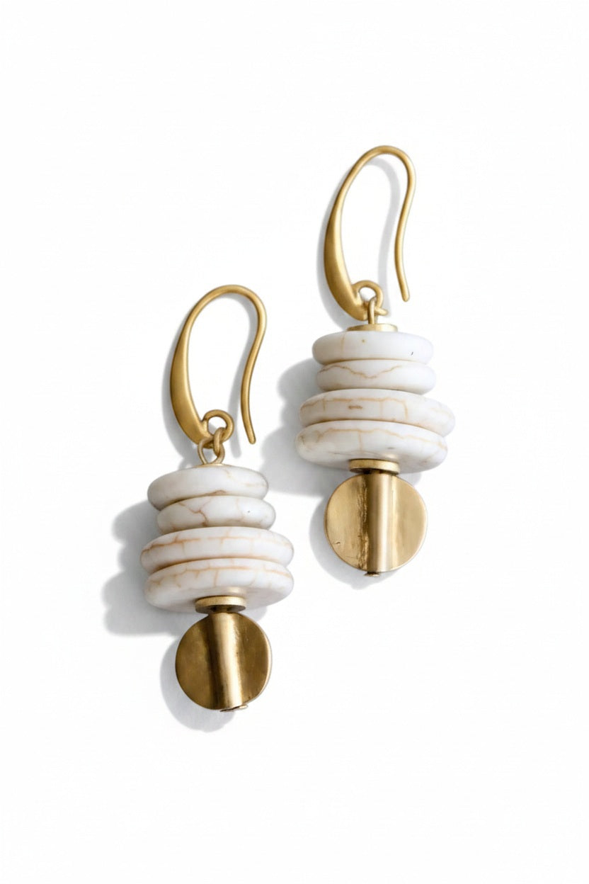 DAVID AUBREY - WHITE MAGNESITE AND BRASS EARRINGS feature stacked white magnesite beads, brass accents, and gold hooks. Handcrafted jewelry by DAVID AUBREY, New Jersey, shown on a gray background.