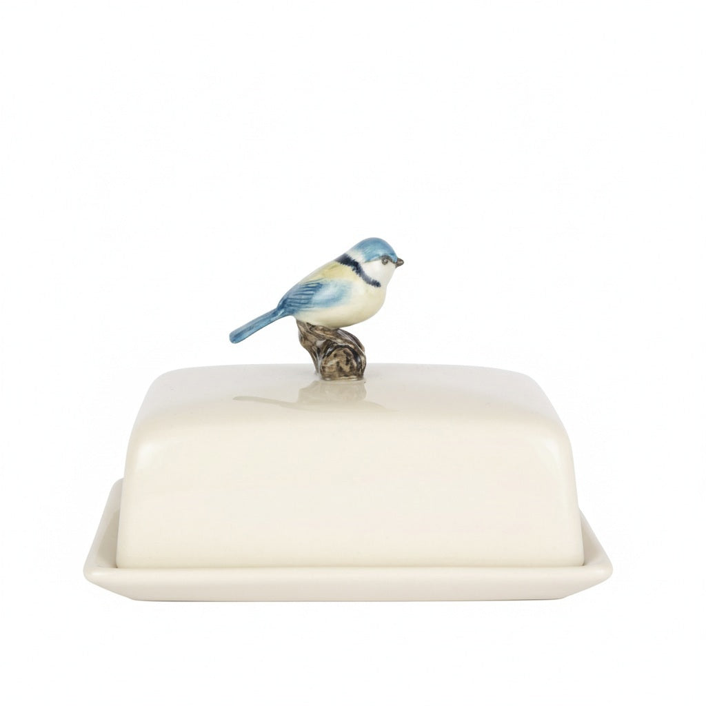 The QUAIL CERAMICS - BLUE TIT BUTTER DISH by QUAIL DESIGNS is a rectangular white butter dish with a lid, topped with a hand-painted blue and white ceramic bird as the handle.