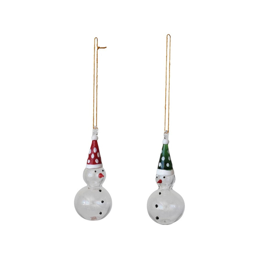 Set of two CREATIVE COOP HANDMADE GLASS SNOWMAN ORNAMENTS with gold strings—each features a round body, painted face with carrot nose, and a pointed hat (one red with white dots, one green).