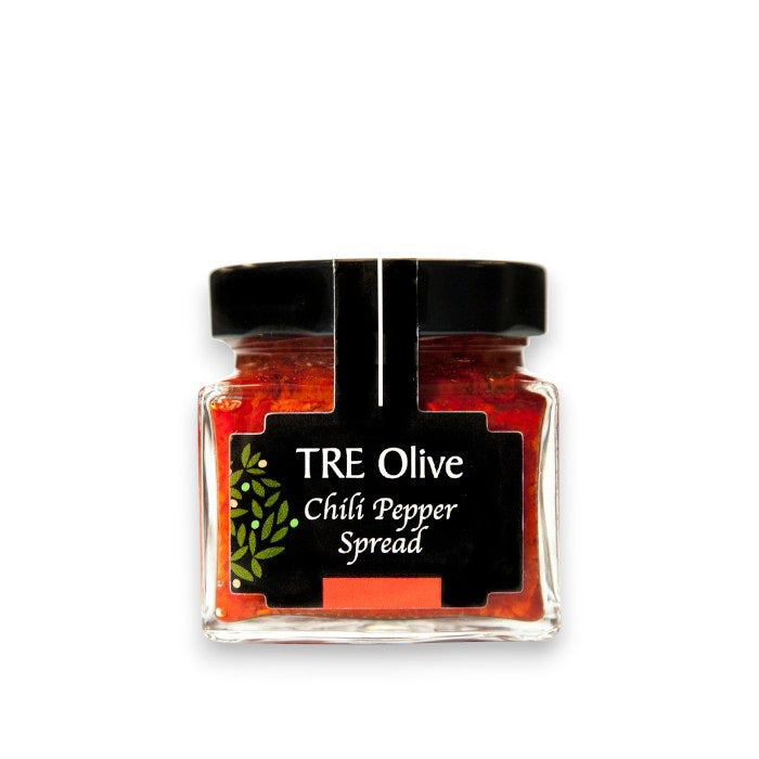 A small glass jar with a black lid contains TRE OLIVE - CALABRIAN CHILI PEPPER SPREAD. The label is black with a green olive branch design and white text. Made in Italy, the bright red spread is visible through the jar, promising rich flavor.