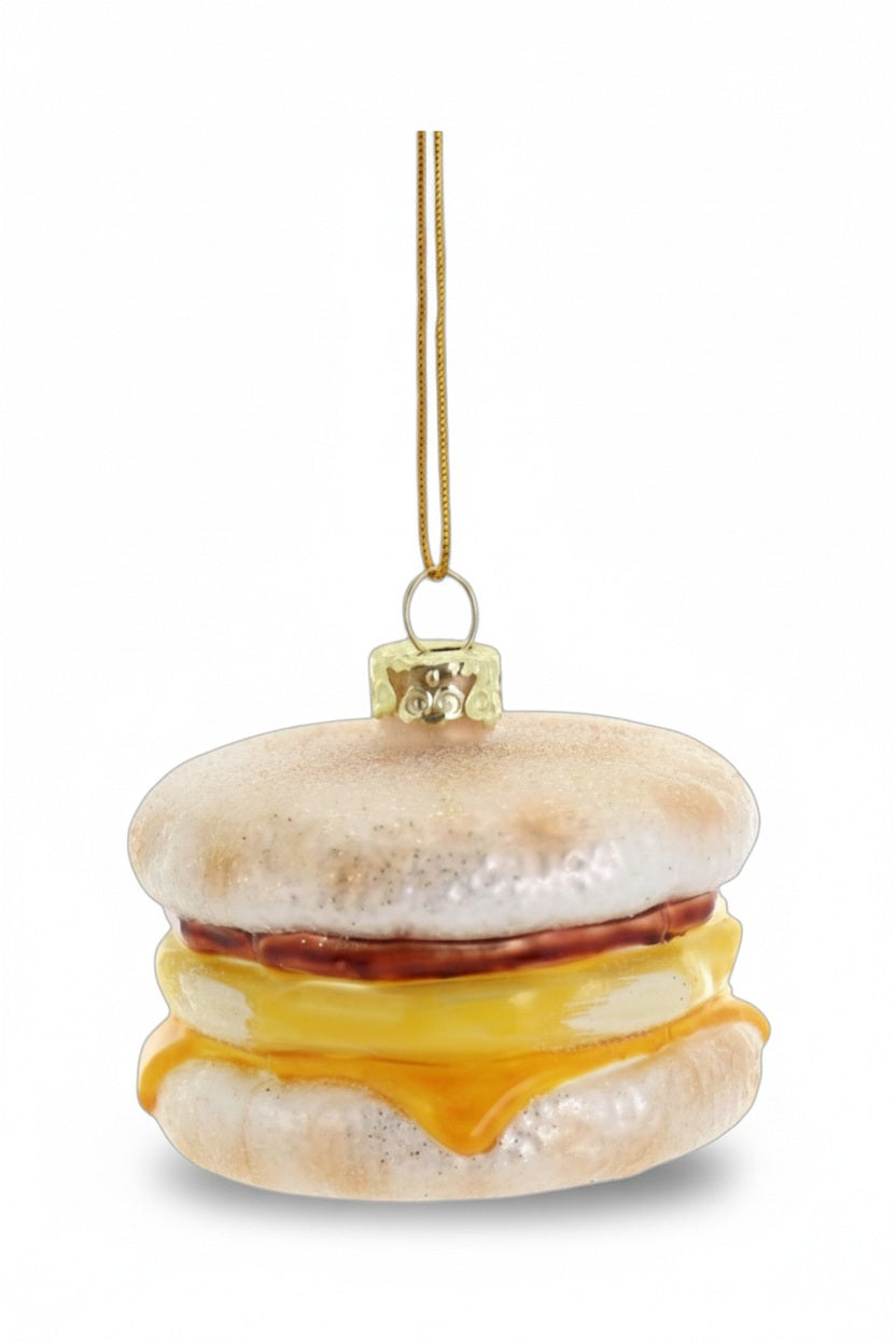 A 2.5-inch EGG MCMUFFIN SANDWICH ORNAMENT by Cody Foster, shaped like an English muffin sandwich with a slice of cheese and meat.