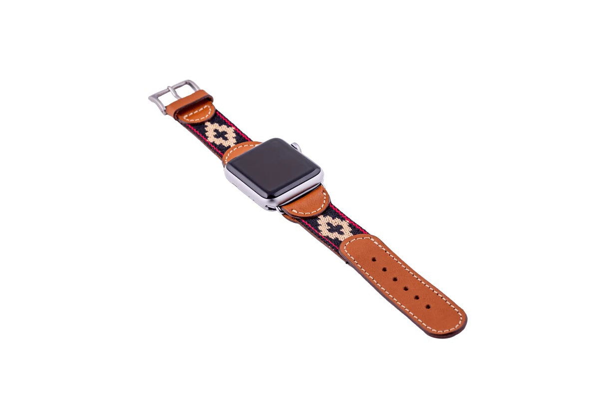 The LA MATERA - CORBINA Apple Watch Band in silver pairs artisan brown leather with a black fabric section, beige geometric pattern, and red stitching.