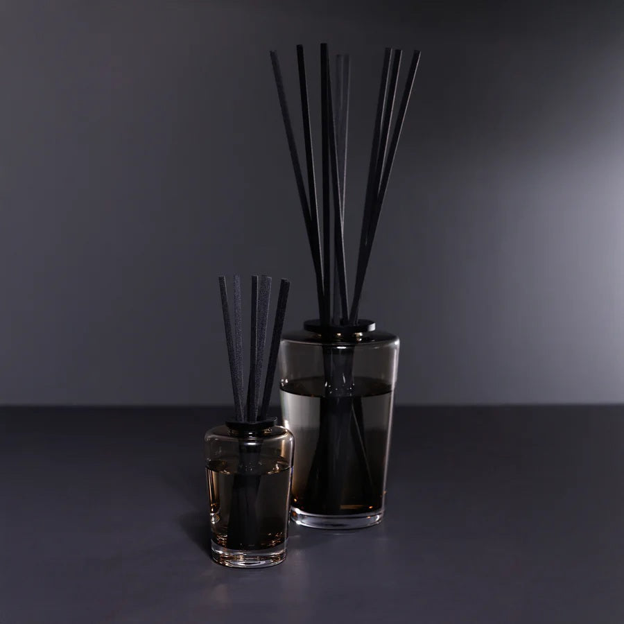 A black rectangular ZODAX gift box with a small label sits beside the THISTLE ESTATE DIFFUSER - 200 ML, featuring black reeds and scented liquid for a refreshing California coast fragrance.