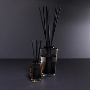 A black rectangular ZODAX gift box with a small label sits beside the THISTLE ESTATE DIFFUSER - 200 ML, featuring black reeds and scented liquid for a refreshing California coast fragrance.