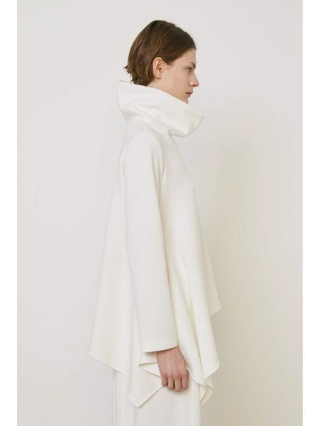 A person with brown hair faces away wearing the MEIMEIJ ASYMMETRICAL COWLNECK TOP in lightweight scuba fabric, featuring an asymmetrical hem, paired with matching white bottoms, against a plain white background.