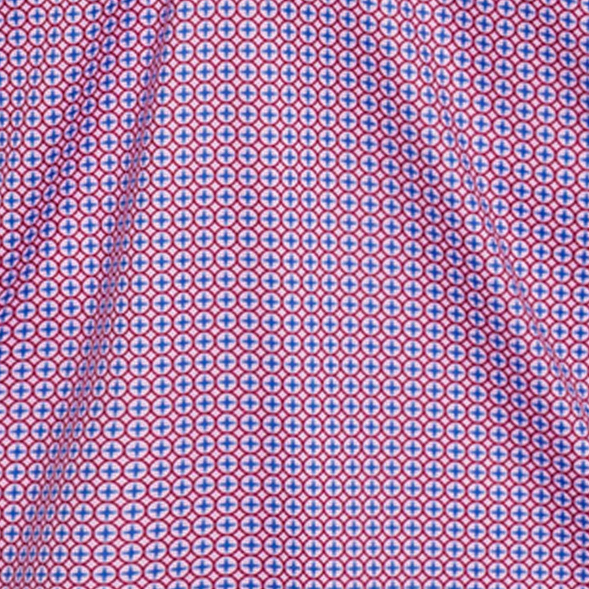 The COLLARS AND CO SEMI SPREAD COLLAR POLO IN CRIMSON COMPASS features a geometric pattern of blue circles and red crosses on white fabric, offering comfort and 4-way stretch for a vibrant, textured look.