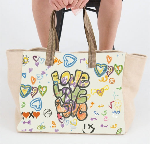 A person holds the STORIATIPIC - TOTE BAG LOVE by STORIATIPIC, a beige cotton bag with brown handles, decorated with colorful hand-drawn hearts and "love love love" in graffiti-style letters on the front.