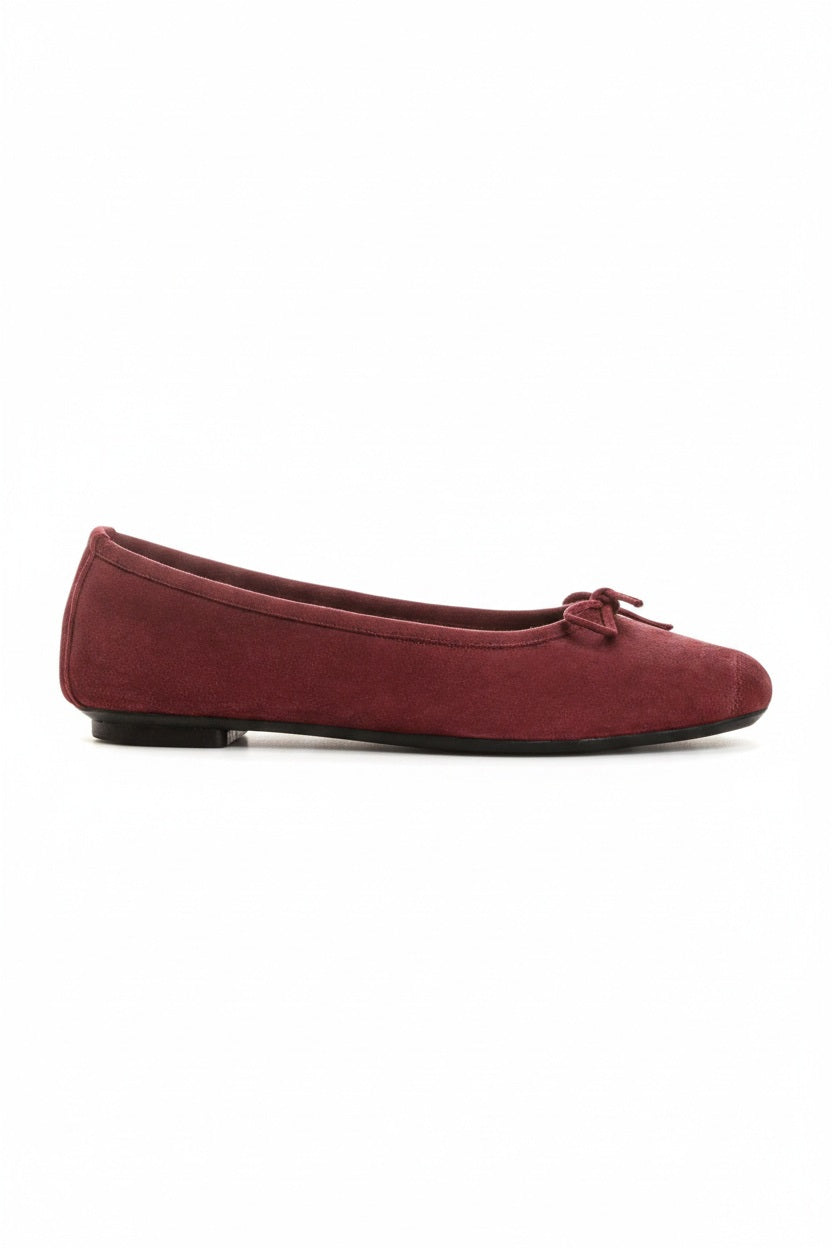The REQINS - HARMONY Suede Ballerina Flats in Bordeaux, featuring elegant small bows on the toes, are displayed on a plain light background.