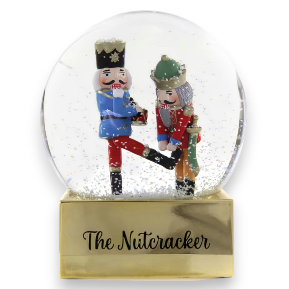 The NUTCRACKER GLOBE ORNAMENT by CODY FOSTER features two nutcrackers—one in blue/red, one in green/red—inside a globe with &quot;The Nutcracker&quot; on a gold base and glitter snow, perfect for collectors or design lovers.