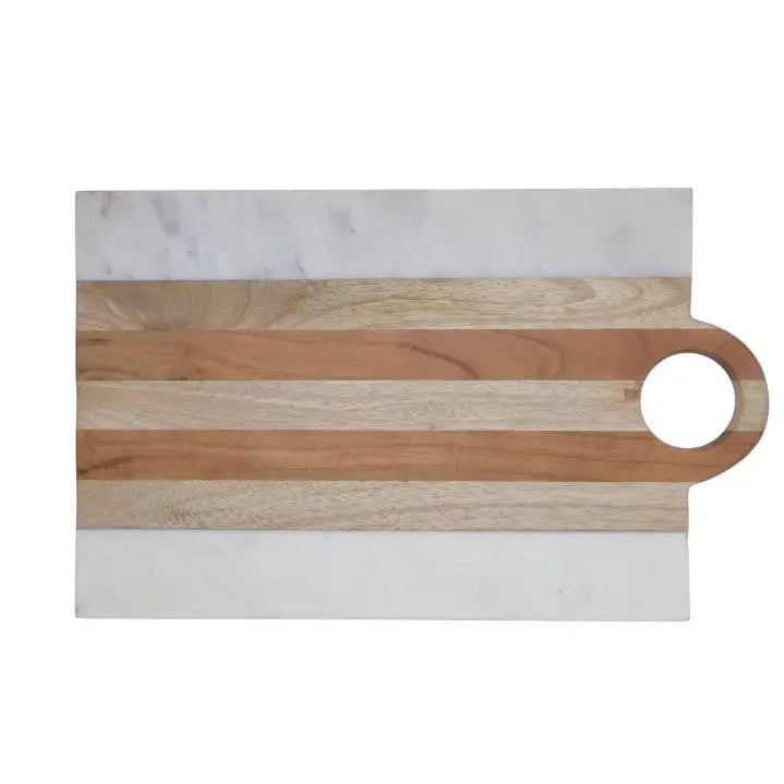 A kitchen scene with three BE HOME - MOA MARBLE & WOOD RECTANGULAR BOARDs by BE HOME, INC, paired with wine, herbs, lemon, cherry tomatoes, bread, olive oil, and spices on a beige surface—highlighting handcrafted home goods.