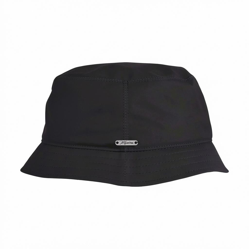 The WIGENS - Waxed Cotton Bucket Hat in Black is a minimalist design crafted from waxed cotton, featuring subtle stitching details and accented with a small metallic tag on the front, shown here against a white background.