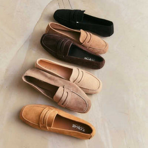 A person stands on a light floor wearing rolled-up blue jeans and REQINS HEMA suede loafers in Marron, showcasing the artisanal craftsmanship of REQINS.