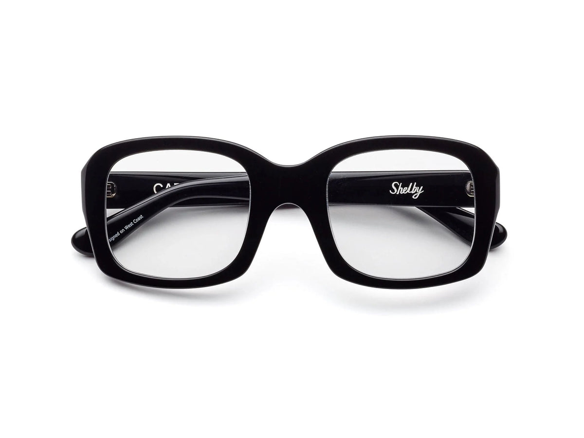 CADDIS - SHELBY PROGRESSIVE READERS by CADDIS are black, square, thick-rimmed eyeglasses with oversized frames and clear, scratch-resistant lenses. Shown front-facing on white; "Shelby" printed in white inside the left arm.