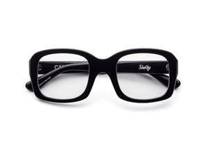 CADDIS - SHELBY PROGRESSIVE READERS by CADDIS are black, square, thick-rimmed eyeglasses with oversized frames and clear, scratch-resistant lenses. Shown front-facing on white; "Shelby" printed in white inside the left arm.
