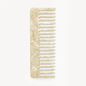 The MACHETE - No. 2 Comb in Ivory, crafted from marbled Italian acetate in a cream hue and featuring wide-set teeth, is displayed vertically against a plain white background.